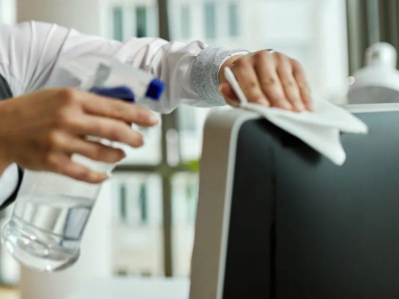 Städare torkar av en datorskärm på ett kontor